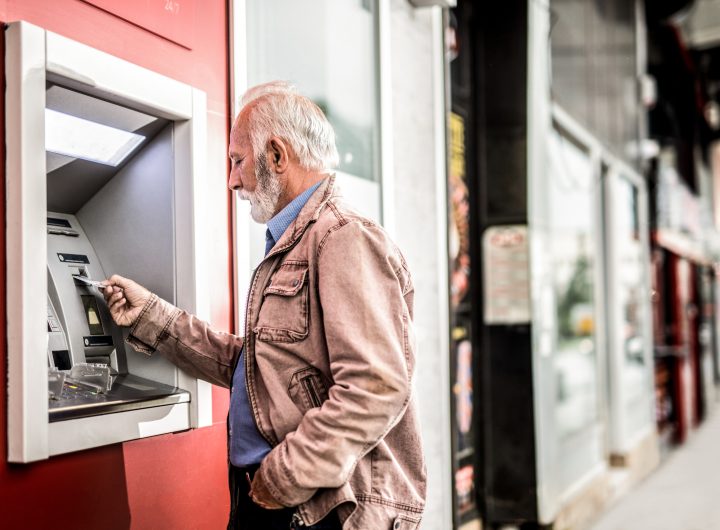 Senior man putting a Credit Card in ATM.