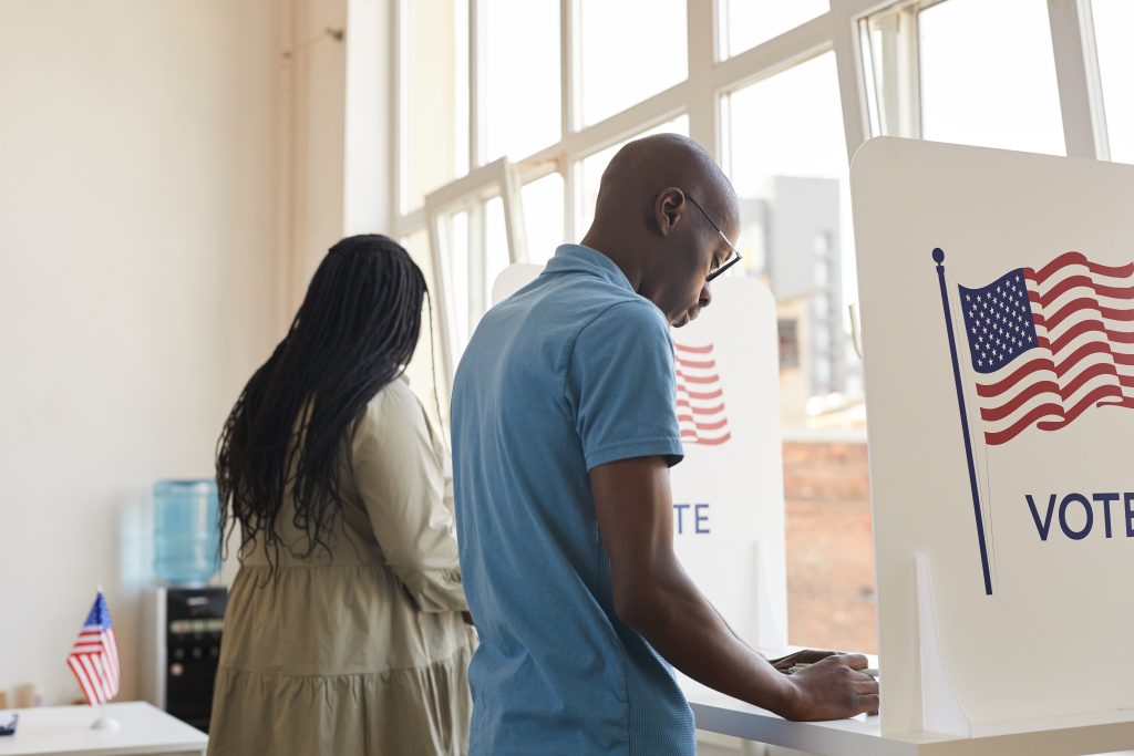 Back view portrait of young African-American people standing in voting booth and thinking, copy space