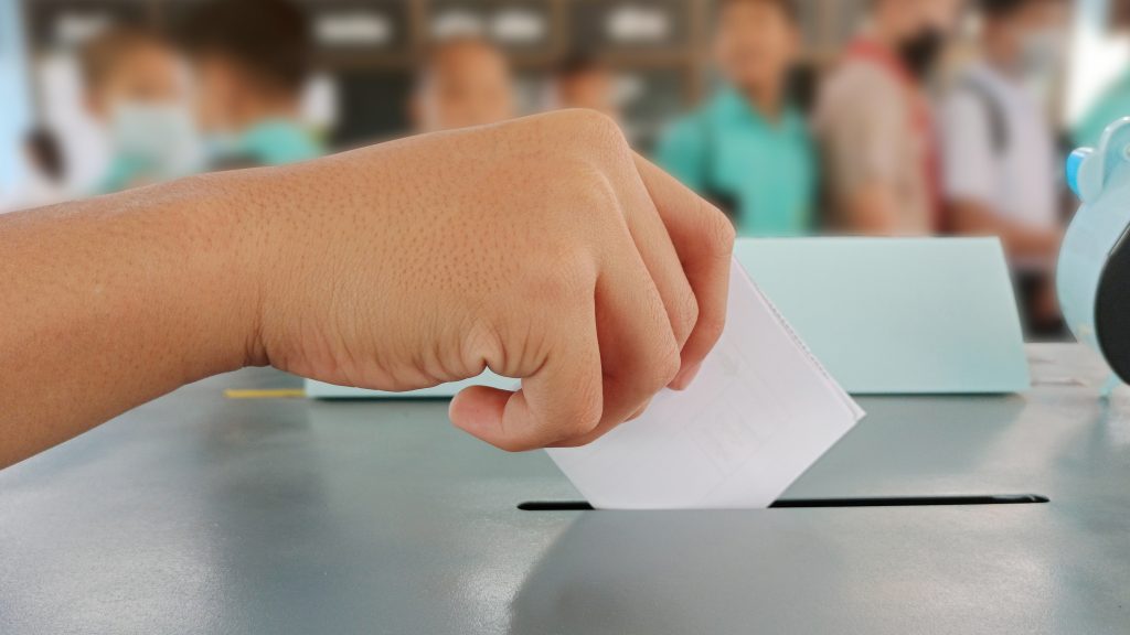 Students hands voting in the ballot box Voters on Election Day for the student council and the school board