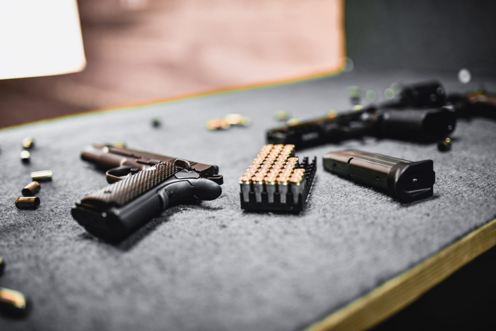 Firearms, Magazines And Cartridges On Shooting Range Booth Table