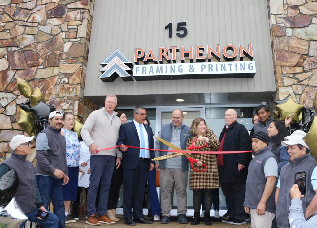 Photo by Hank Russell
Flanked by their employees, Parthenon Framing & Printing Owner George Bubaris (center) and his wife, Business Manager Joan Bubaris (second from right, holding scissors), get ready to cut the ribbon to celebrate the grand opening of their business. Also pictured (left to right): Brookhaven Town Councilman Neil Foley, Suffolk County Legislator Dominick Thorne, and Medford Chamber of Commerce President Paul Donoghue.