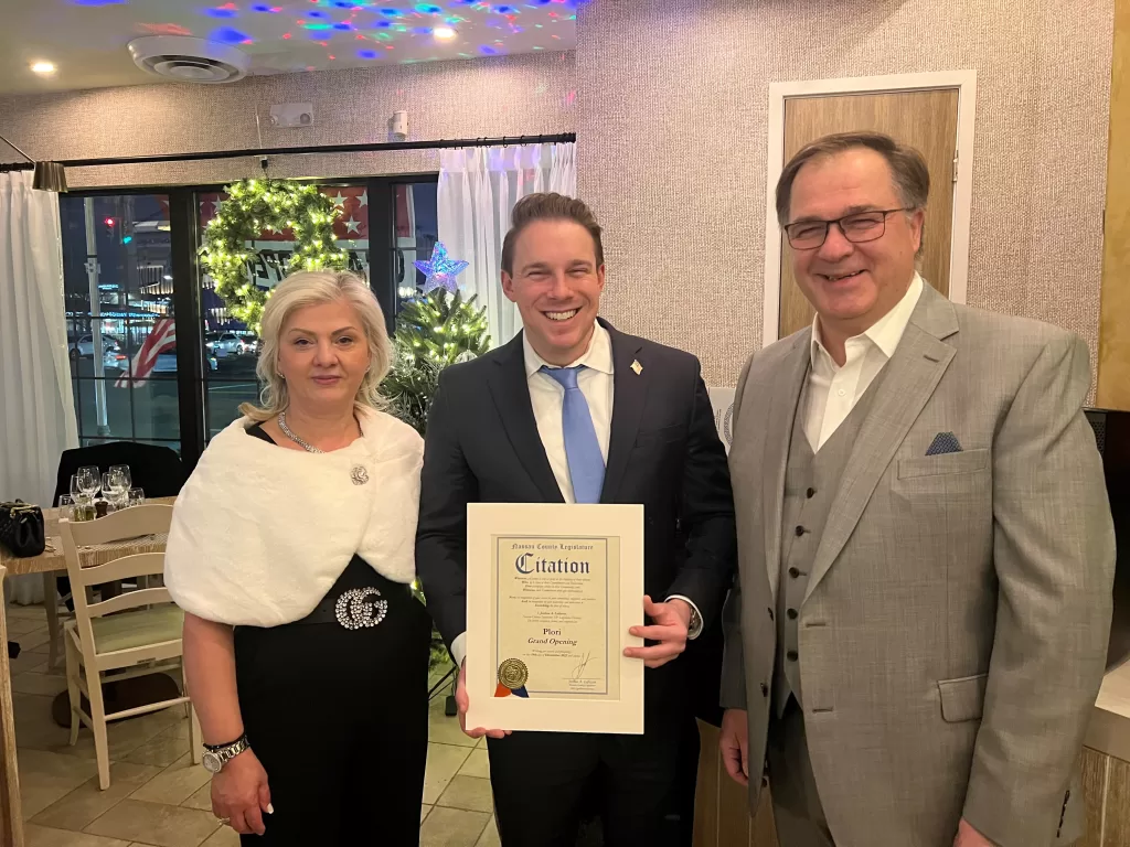 (Photo: Office of Legislator Joshua A. Lafazan) Nassau County Joshua A. Lafazan (center) presents a citation celebrating the grand opening of Plori Restaurant in Carle Place to Owners Buffy Dimas (left) and Spiro Dimas (right).