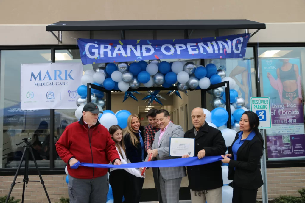 (Photo by Hank Russell) Dr. Ron Mark (third from right) cuts the ribbon with his daughter Avery (second from left), his wife Kimberly (third from left), his son Preston (center) — during the grand opening of Mark Medical Care on January 21. Also pictured (left to right): Medford Chamber of Commerce President Paul Donoghue, New York State Assemblyman Joe DeStefano, and Mark Medical Care Marketing Director Lizette Herrera.