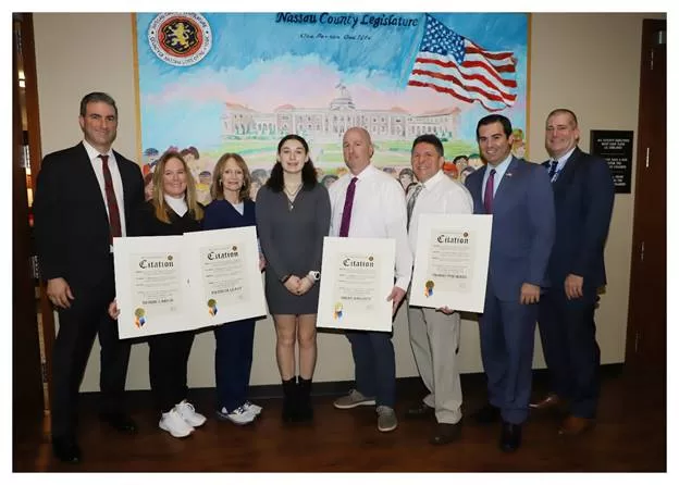 (Photo: Office of Legislator John Ferretti) Nassau County Legislator John Ferretti (second from right) poses with the faculty and staff of Division Avenue High School and student Haeleigh Ortiz (fourth from left).