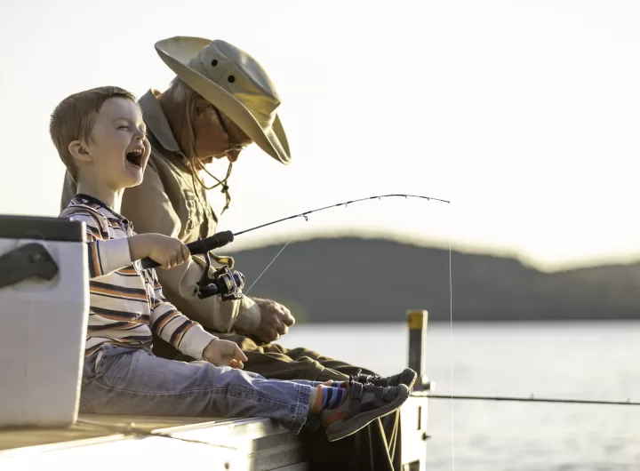 Grandfather and Grandson Fishing At Sunset in Summer