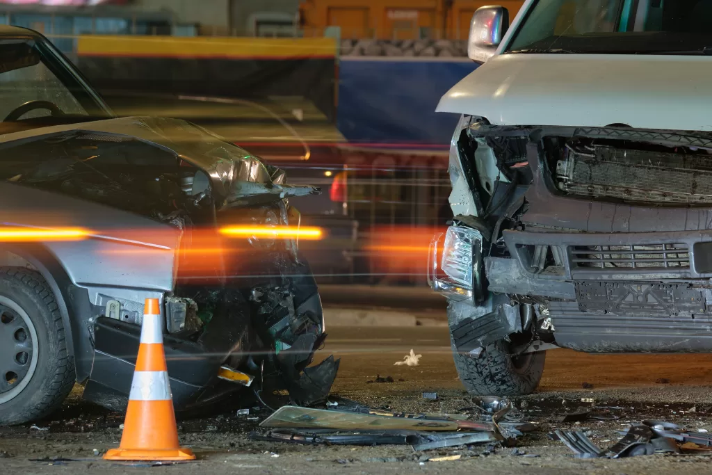 Damaged in heavy car accident vehicles after collision on city street crash site at night. Road safety and insurance concept