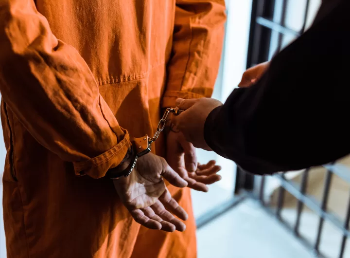 cropped image of prison officer wearing handcuffs on prisoner