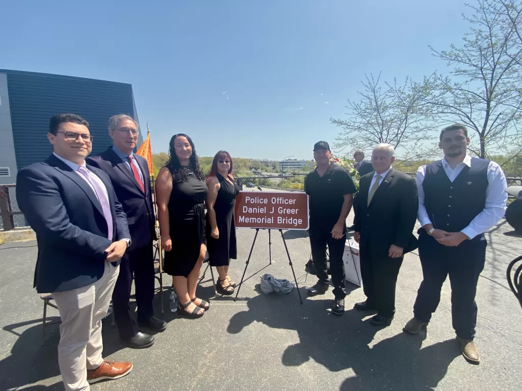 (Photo Courtesy of the Office of Charles Lavine) NYS Assemblymember Charles Lavine
(second from right) and former NYS Senator James Gaughran (second from left) present the
family of Officer Daniel J. Greer with a commemorative sign at a ceremony in Plainview on
April 21.
