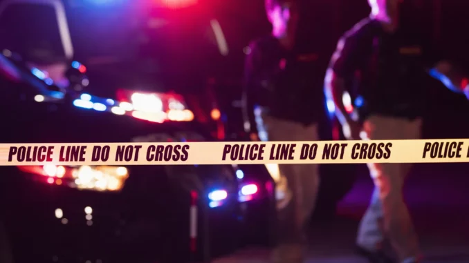 Two police officers behind crime scene tape