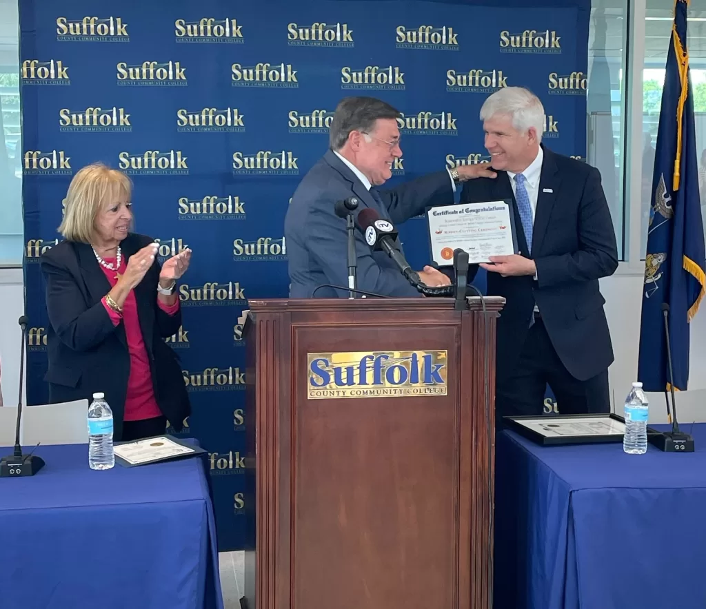 (Photo: Town of Brookhaven) Brookhaven Town Supervisor Ed Romaine (center) presents a Certificate of Congratulations to Suffolk County Community College President Dr. Edward Bonahue (right) at the grand opening of the Renewable Energy/STEM Center in Brentwood on June 1. Also pictured is Islip Town Supervisor Angie Carpenter (left).