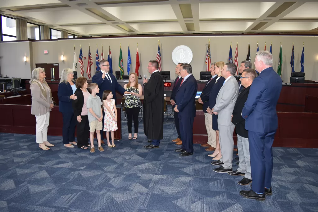 (Photo: Town of Brookhaven) Neil Manzella (fifth from right) was sworn in by District Court Judge Evan Zuckerman (center) while surrounded by family members, including (left to right) his aunt Nancy Poulos, mother Betty Manzella, grandmother Mary Vetrano, son Neil Manzella, daughter Layla Manzella, and wife Rebecca Manzella.