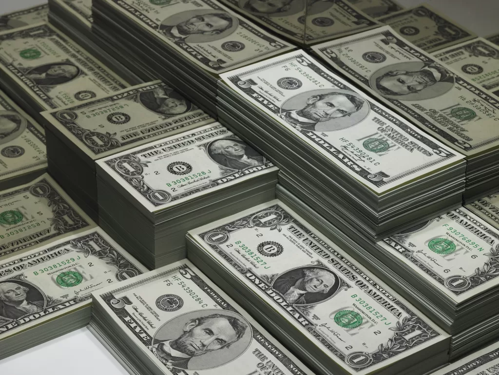 piles of dollar bills reflected in glass