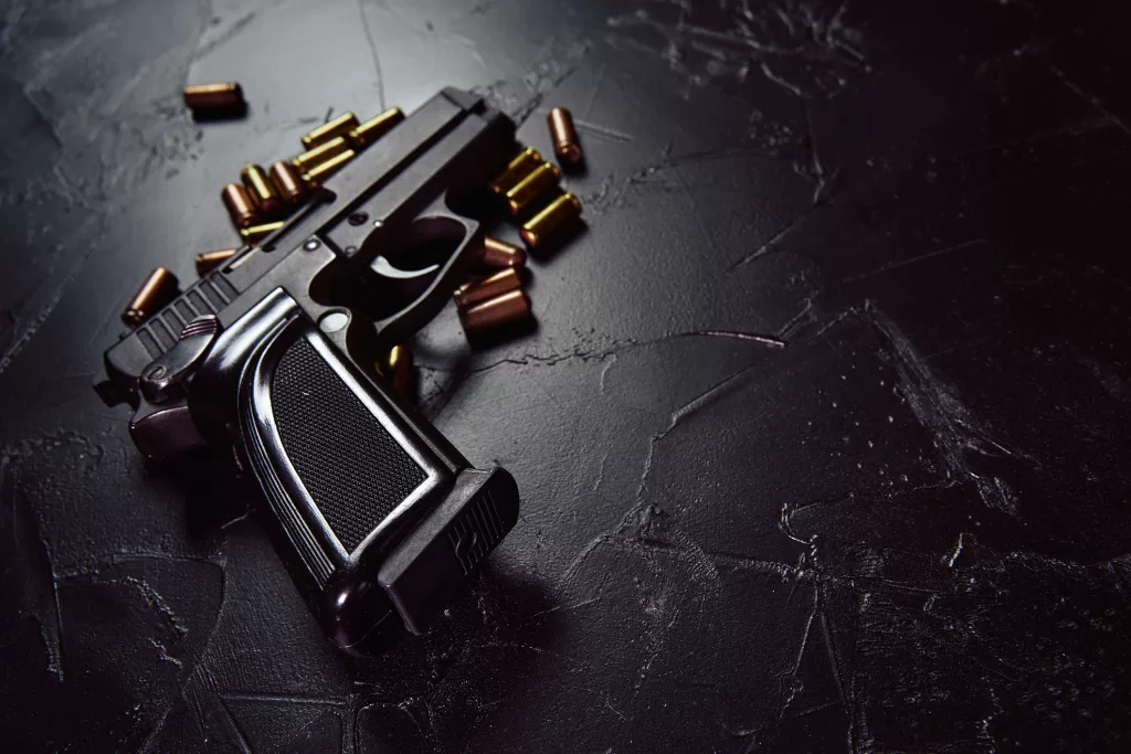 Pistol with cartridges on black concrete table.