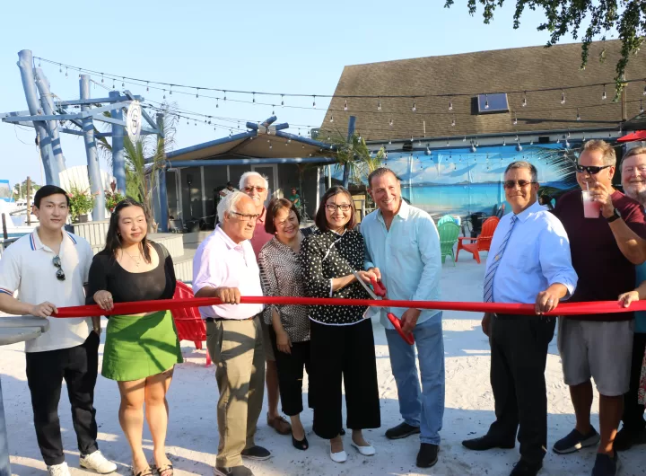(Photo by Hank Russell) Baja Boathouse co-owners Hong Liu (center) and Lenny Oliva (fourth from right) cut  the ribbon on the grand opening of their cantina/restaurant/marina in Patchogue on August 9. Also pictured (left to right): Liu’s son Vinci and her daughter Emmy, Patchogue Village Mayor Paul Pontieri, Liu’s friend Eileen Lin, Suffolk County Legislator Dominick Thorne, customer Bruce Rosenberg and Patchogue Village Business Improvement District Executive Director Dennis Smith.