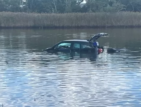 (Photo Courtesy of SCPD) A BMW i3 went through a guardrail then landed in the Forge River in Mastic.