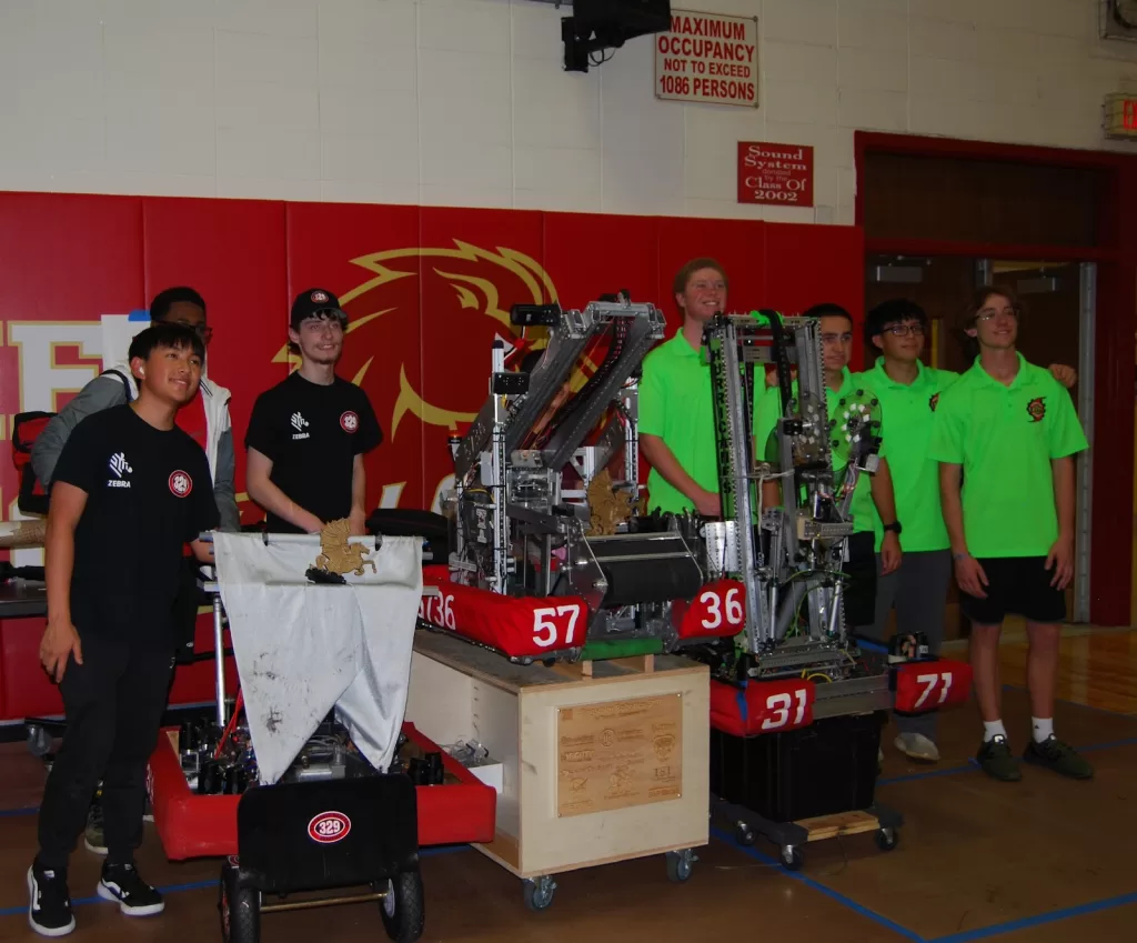 (Photo: FIRSTⓇ Long Island) Patchogue-Medford “Mohawks” (Team #329), Kings Park “Kingsmen” (Team #5736) and Westhampton Beach “HURRICANES” (Team #3171) pose with their winning robots and first-place trophies at the Half Hollow Hills Invitational on October 28.