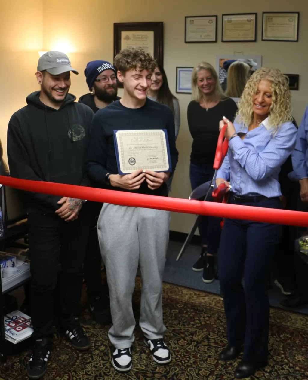 (Photo by Hank Russell) Maria Scheuring (right) prepares to cut the ribbon in celebration of her new office at 1 South Ocean Avenue, Suite 204A, in Patchogue. She is joined by Ron Ulip (left), the owner of Freshly Cut Films, and her son Maddox (center).