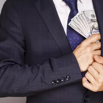 Businessman putting money in suit jacket pocket