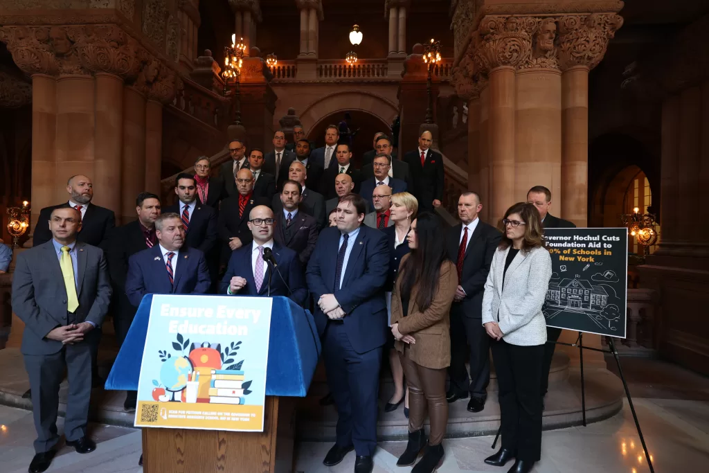 (Photo: New York State Assembly Minority) New York State Assemblyman Ed Ra (standing behind podium) spoke out against the proposed education cuts by Governor Kathy Hochul during a gathering of GOP Assembly members, parents and education stakeholders in Albany on January 22.