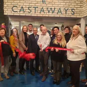 (Photo by Caitlyn Crudden) Castaways Co-Owner John Sarno (center) prepares to cut the ribbon with Co-Owners Mike Krohn (third from left) and Mario Tucci (third from right) for the grand opening of their restaurant in Port Jefferson. Also pictured are Port Jefferson Village Deputy Mayor Rebecca Kassay (left) and Village Mayor Lauren Sheprow (second from left). 