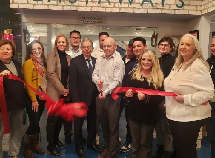 (Photo by Caitlyn Crudden) Castaways Co-Owner John Sarno (center) prepares to cut the ribbon with Co-Owners Mike Krohn (third from left) and Mario Tucci (third from right) for the grand opening of their restaurant in Port Jefferson. Also pictured are Port Jefferson Village Deputy Mayor Rebecca Kassay (left) and Village Mayor Lauren Sheprow (second from left). 