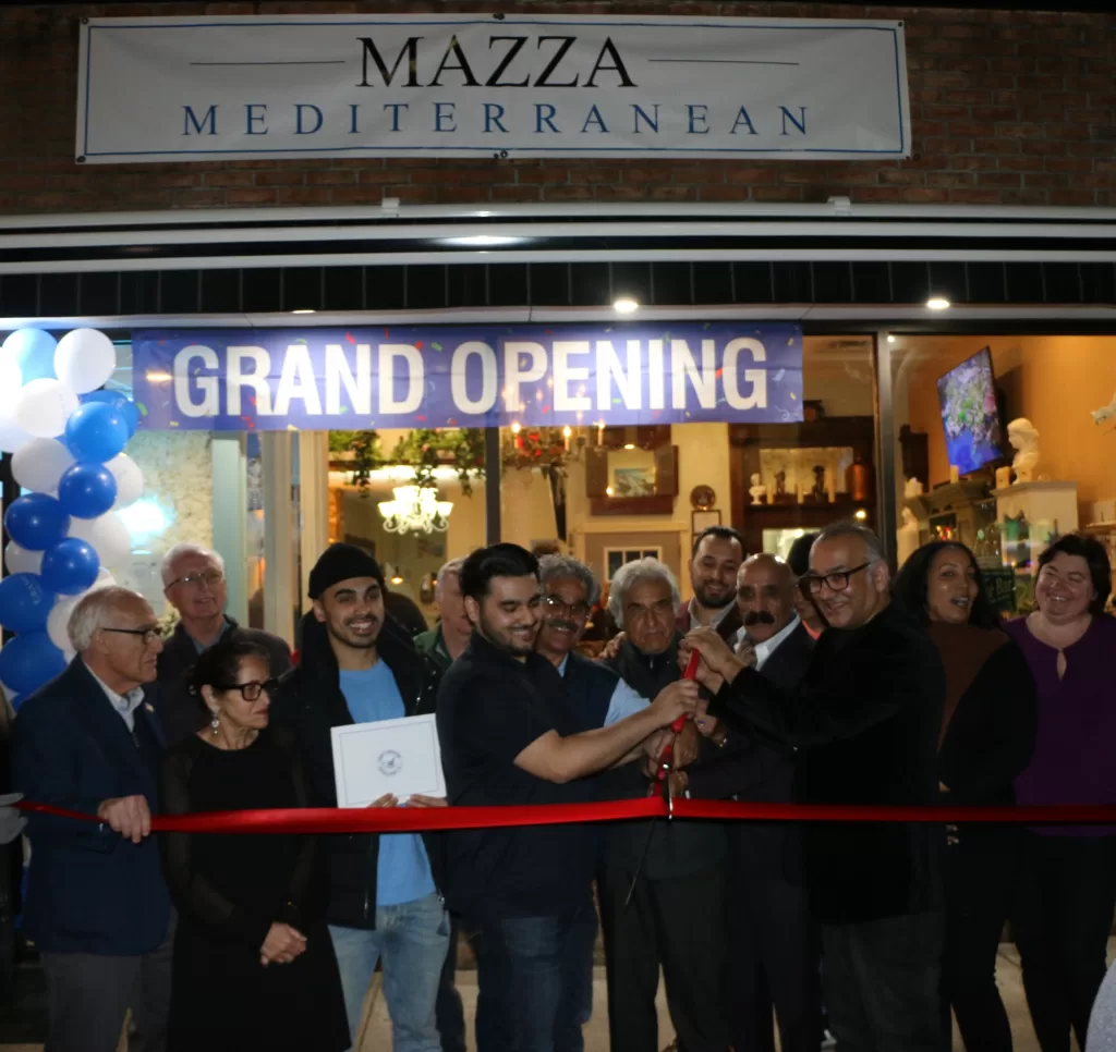 (Photo: Hank Russell) Owner Sam Omar (left) and his father, Wais Omar (right) cut the ribbon together to celebrate the grand opening of Mazza Mediterranean Cuisine in Patchogue on February 9.
