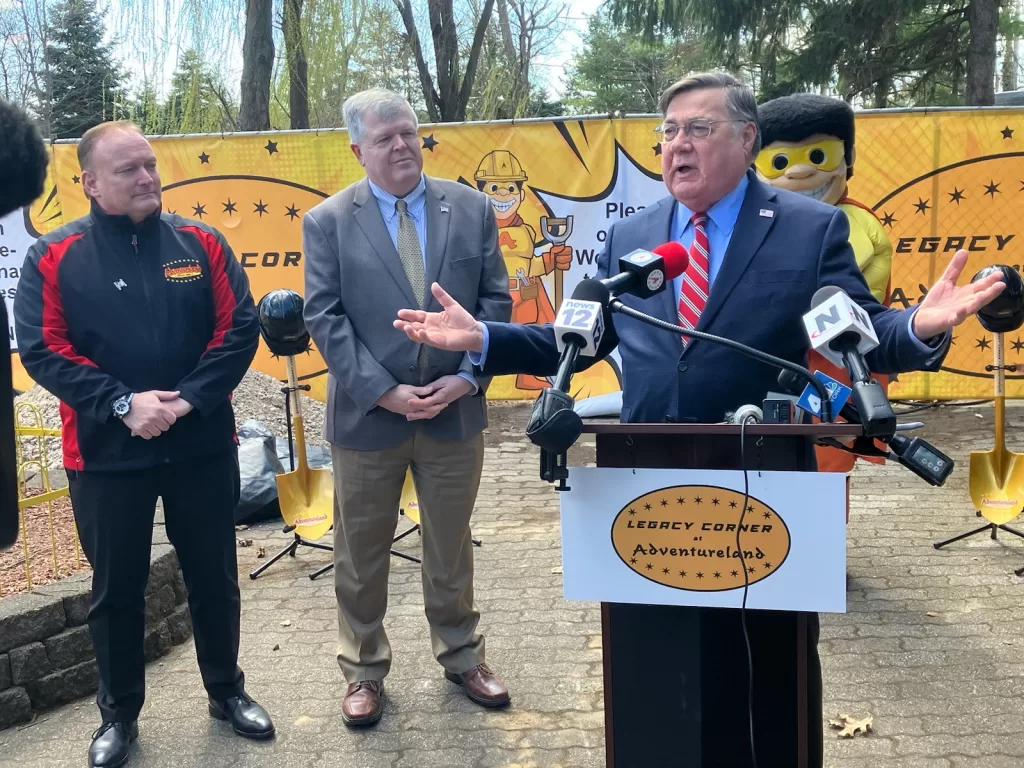 (Photo Courtesy of Adventureland) Suffolk County Executive Ed Romaine (behind podium) speaks at Adventureland, where the amusement park is undergoing a $10 million renovation over five years and recently entered into a partnership with Catholic Health. Also pictured are Adventureland President Steve Gentile (left) and Babylon Town Supervisor Rich Shaffer (second from left).