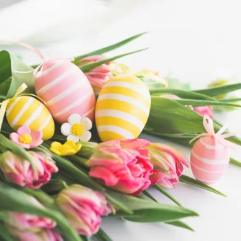 Stylish dyed easter eggs with spring flowers on white background.