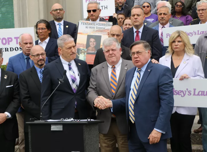 (Photo: Hank Russell) Babylon Town Supervisor Rich Schafer (center) and Suffolk County Executive Ed Romaine (right) shake hands in solidarity at a press conference calling for the passage of Chelsey's Law on May 17 as Chief Assistant DA Allen Bode (left) looks on.