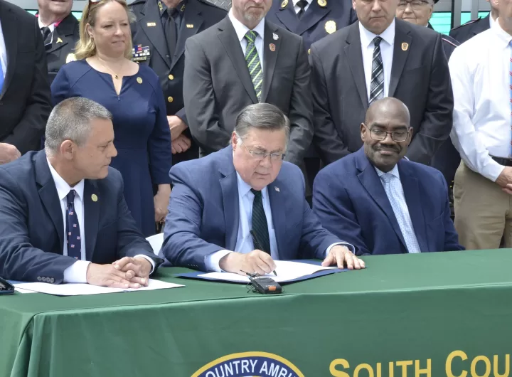 (Photo: Suffolk County Legislature) Suffolk County Executive Ed Romaine signs into law Suffolk Legislator Dominick
Thorne’s bill designating the third week in May 2024, and every year thereafter, as “EMS
Appreciation Week” in Suffolk County. At table, Romaine (center) is flanked by Thorne (left) and
Suffolk Department of Heath Services Commissioner Gregson H. Pigott, MD, MPH (right). They
were joined at the South Country Ambulance Company HQ in Bellport, NY, by members of over
twenty EMS agencies from across Suffolk County.
