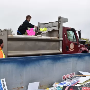 (Photo: Town of Brookhaven) A highway crew member from the Town of Brookhaven discards an illegal sign into a Dumpster.