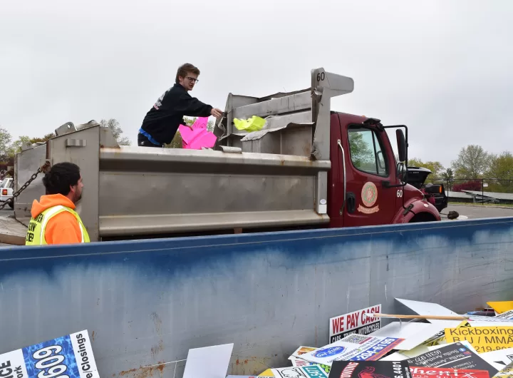(Photo: Town of Brookhaven) A highway crew member from the Town of Brookhaven discards an illegal sign into a Dumpster.