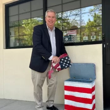 Huntington Town Republican Committee Chairman Tom McNally is pictured placing a worn American flag in the Huntington GOP Committee’s drop-off bin.
