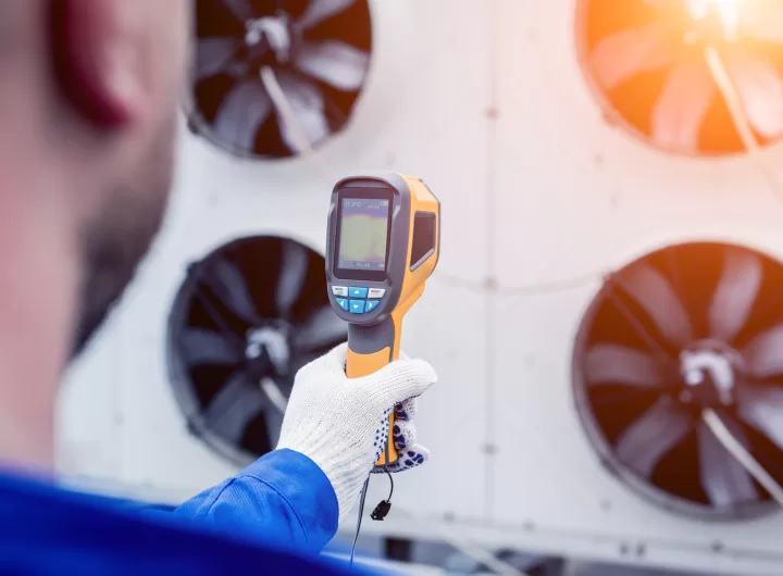 Technician uses a thermal imaging infrared thermometer to check the condensing unit heat exchanger