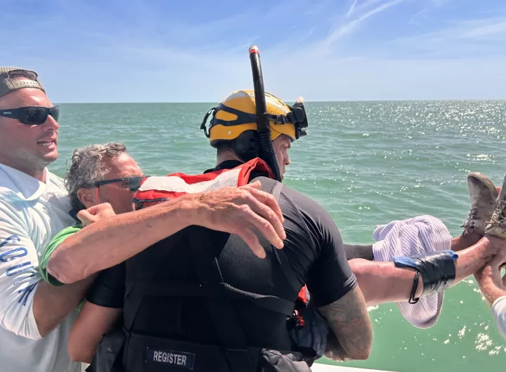 (Photo Courtesy of SCPD) Officer William Parmenter (left) and a Coast Guard officer bring Norman Orsinger to safety after Orsinger suffered a serious injury on his boat.