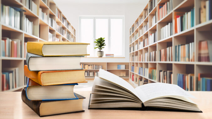 Book stack and open book on the desk in modern public library