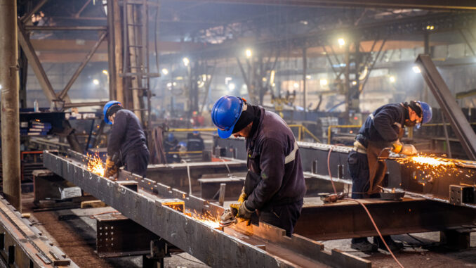 Metal workers using a grinder