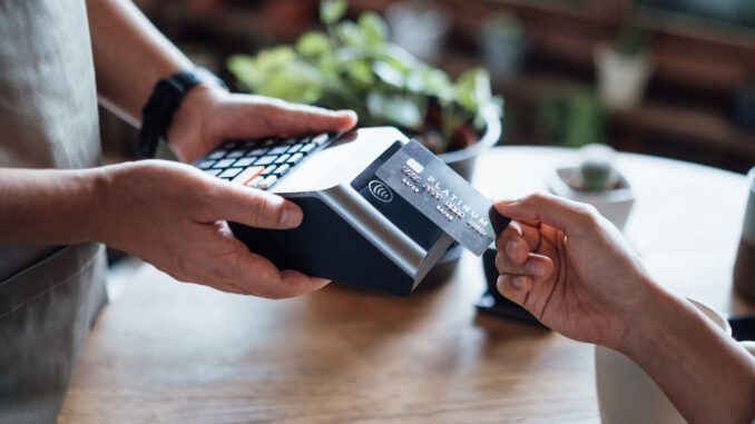 Close up of a woman's hand paying bill with credit card in a cafe, scanning on a card machine. Electronic payment. Banking and technology