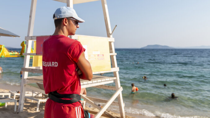Back view of a young male lifeguard on the beach. Summer vacation