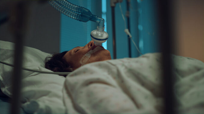 Sick woman wearing oxygen mask portrait. Terminally ill person lying in ward.